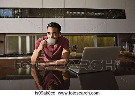 Young man in dining room drinking coffee View Large Photo Image Stock Image - Young man in dining room drinking coffee. Fotosearch