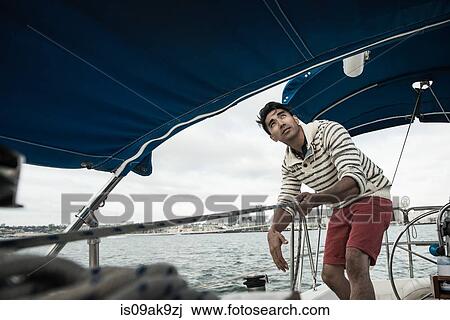 Young man looking up on sailing boat View Large Photo Image Stock Image - Young man looking up on sailing boat. Fotosearch