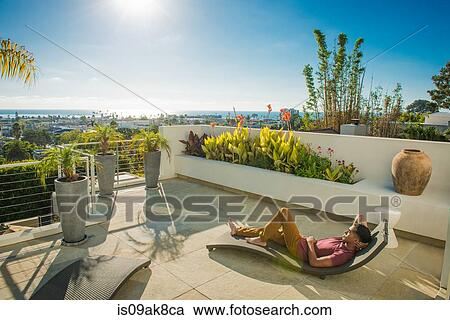 Young man lying on lounger in penthouse rooftop garden, La Jolla, California, USA View Large Photo Image Stock Image - Young man lying on lounger in penthouse rooftop garden, La Jolla, California, USA. Fotosearch