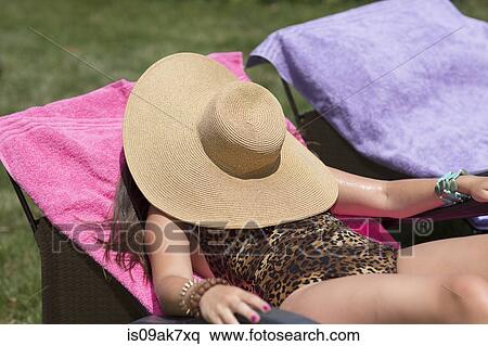 Young woman hiding under sunhat sunbathing on lounger in garden View Large Photo Image Stock Photography - Young woman hiding under sunhat sunbathing on lounger in garden. Fotosearch