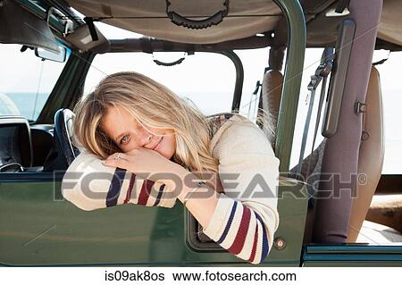 Stock Photograph - Young woman leaning out of jeep window. Fotosearch