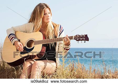 Young woman playing acoustic guitar at coast, Malibu, California, USA View Large Photo Image Stock Photo - Young woman playing acoustic guitar at coast, Malibu, California, USA. Fotosearch