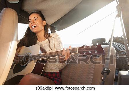 Young woman playing acoustic guitar in back of jeep View Large Photo Image Stock Image - Young woman playing acoustic guitar in back of jeep. Fotosearch