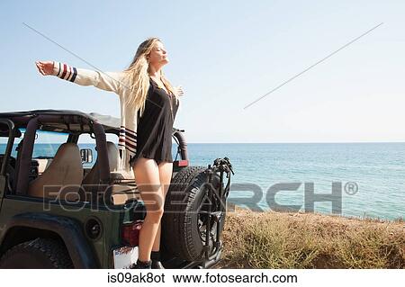 Young woman standing on back of jeep at coast with arms outstretched, Malibu, California, USA View Large Photo Image Stock Photograph - Young woman standing on back of jeep at coast with arms outstretched, Malibu, California, USA. Fotosearch