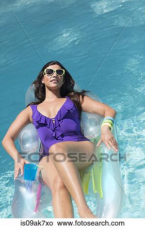 Young woman sunbathing on air bed in swimming pool View Large Photo Image Picture - Young woman sunbathing on air bed in swimming pool. Fotosearch