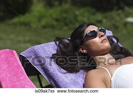 Young woman sunbathing on lounger in garden View Large Photo Image Stock Photograph - Young woman sunbathing on lounger in garden. Fotosearch