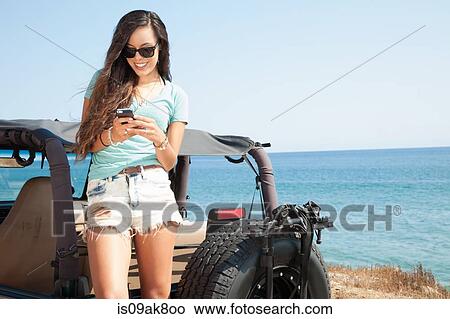 Young woman texting on smartphone at coast, Malibu, California, USA View Large Photo Image Picture - Young woman texting on smartphone at coast, Malibu, California, USA. Fotosearch