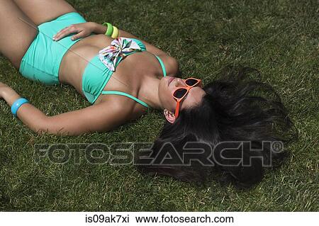 Young woman wearing bikini sunbathing on lawn View Large Photo Image Stock Image - Young woman wearing bikini sunbathing on lawn. Fotosearch