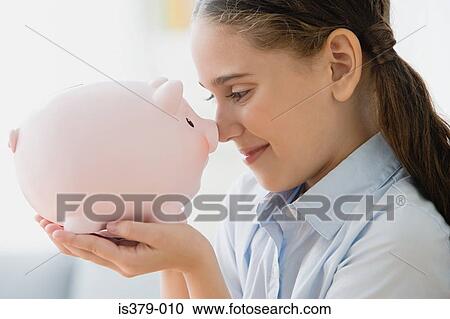 Stock Image - Girl holding a piggy bank. Fotosearch