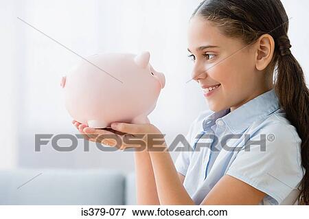 Girl holding a piggy bank View Large Photo Image Stock Photo - Girl holding a piggy bank. Fotosearch