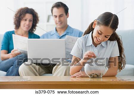 Stock Photography - Girl putting coins in a piggy bank. Fotosearch