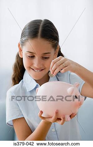 Stock Image - Girl saving a coin in piggy bank. Fotosearch