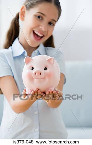 Smiling girl holding a piggy bank View Large Photo Image Stock Photo - Smiling girl holding a piggy bank. Fotosearch