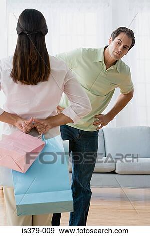 Woman hiding shopping bags from husband View Large Photo Image Stock Photo - Woman hiding shopping bags from husband. Fotosearch