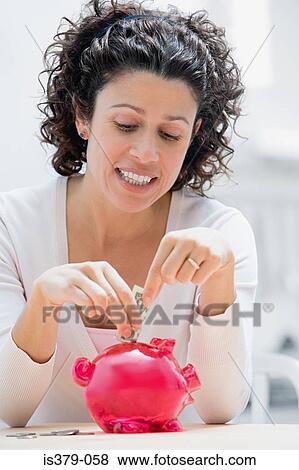 Woman putting money in piggy bank View Large Photo Image Stock Photo - Woman putting money in piggy bank. Fotosearch