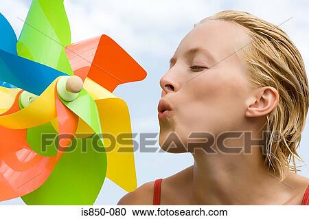 Stock Image - Woman blowing pinwheel. Fotosearch