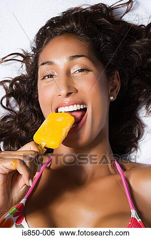 Stock Photograph - Woman eating ice lolly. Fotosearch