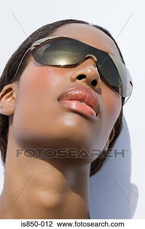 Stock Image - Young woman wearing sunglasses. Fotosearch
