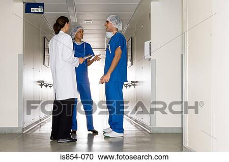 Stock Image - Doctor and surgeons in corridor. Fotosearch