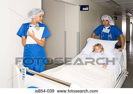 Stock Photo - Surgeons taking girl through corridor. Fotosearch