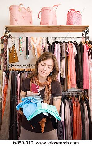 Stock Image - A woman looking at price tags. Fotosearch