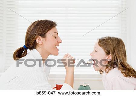 Mother feeding daughter breakfast View Large Photo Image Stock Photo - Mother feeding daughter breakfast. Fotosearch