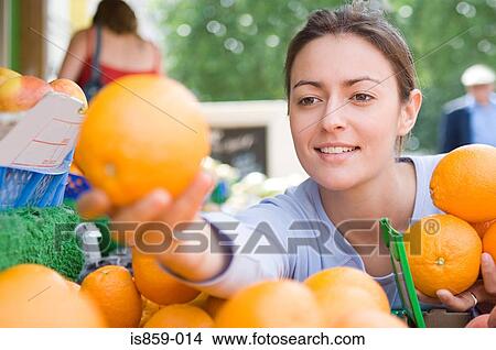 Picture - Woman choosing oranges. Fotosearch