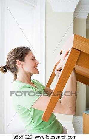 Stock Image - Woman moving table. Fotosearch