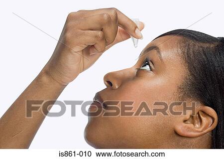 Stock Image - Woman using eye drops. Fotosearch