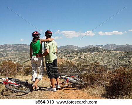 Stock Image - Couple with bikes looking at view. Fotosearch