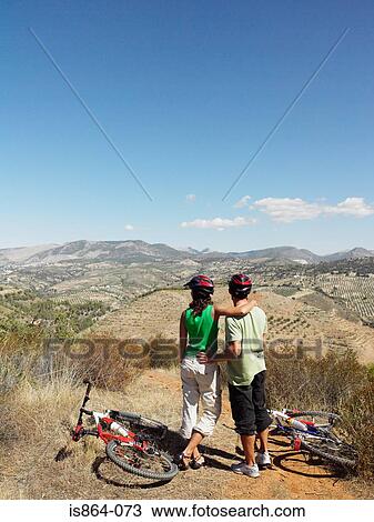 Stock Image - Couple with bikes looking at view. Fotosearch