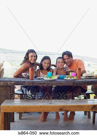 Stock Image - Family having meal outdoors. Fotosearch