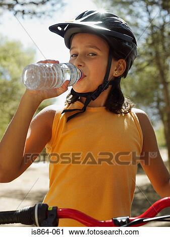 Girl on a bike drinking water View Large Photo Image Stock Image - Girl on a bike drinking water. Fotosearch