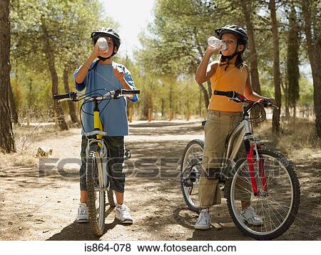 Kids on bikes drinking water View Large Photo Image Stock Photo - Kids on bikes drinking water. Fotosearch