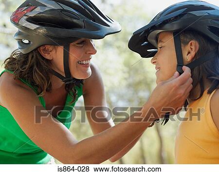 Mother putting bicycle helmet on girl View Large Photo Image Stock Photo - Mother putting bicycle helmet on girl. Fotosearch