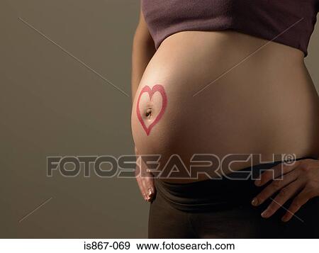 Heart on pregnant womans stomach View Large Photo Image Stock Photo - Heart on pregnant womans stomach. Fotosearch