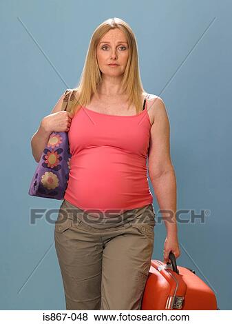 Stock Photo - Pregnant woman carrying suitcase. Fotosearch
