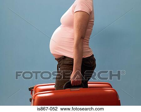 Stock Image - Pregnant woman carrying suitcases. Fotosearch