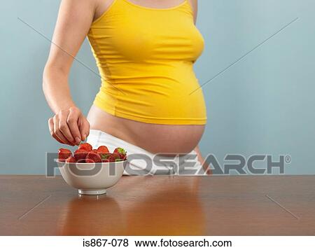 Pregnant woman choosing a strawberry View Large Photo Image Stock Photo - Pregnant woman choosing a strawberry. Fotosearch