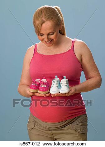 Pregnant woman holding baby shoes View Large Photo Image Stock Image - Pregnant woman holding baby shoes. Fotosearch