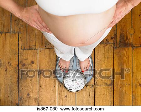 Pregnant woman standing on scales View Large Photo Image Stock Image - Pregnant woman standing on scales. Fotosearch