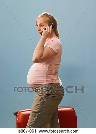 Pregnant woman using telephone and holding suitcase View Large Photo Image Stock Image - Pregnant woman using telephone and holding suitcase. Fotosearch
