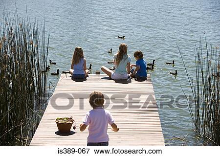Children feeding ducks on a lake View Large Photo Image Stock Photo - Children feeding ducks on a lake. Fotosearch