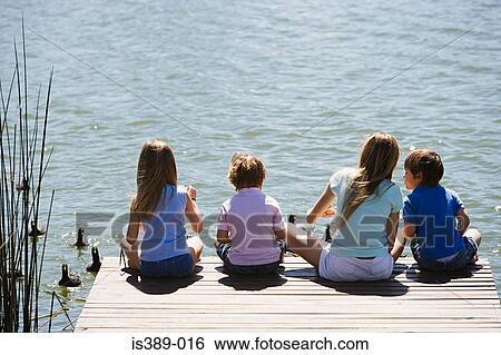 Children feeding ducks on a lake View Large Photo Image Stock Photograph - Children feeding ducks on a lake. Fotosearch