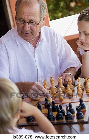 Grandfather playing chess with grandchildren View Large Photo Image Stock Photo - Grandfather playing chess with grandchildren. Fotosearch