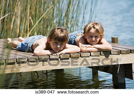 Stock Photo - Two boys lying on decking. Fotosearch