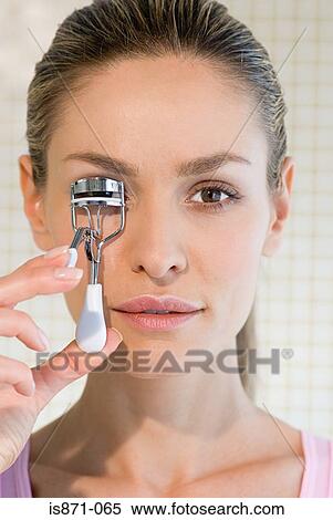 Stock Photography - Woman curling eyelashes. Fotosearch
