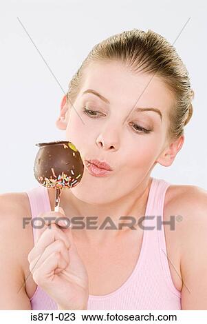 Stock Image - Woman eating chocolate apple. Fotosearch