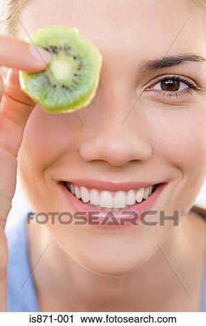 Stock Image - Woman holding kiwi fruit. Fotosearch