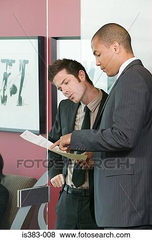 Two businessmen looking at paperwork View Large Photo Image Stock Photo - Two businessmen looking at paperwork. Fotosearch